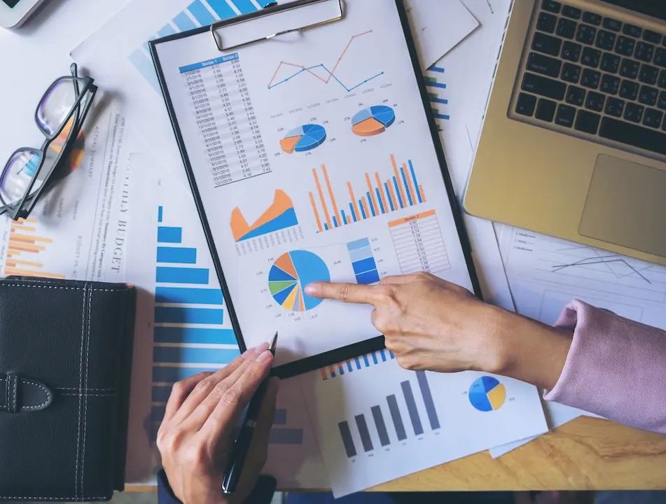 Fotografia di Wealth Advisor Euclidea al lavoro con diversi documenti sul tavolo e un computer portatile